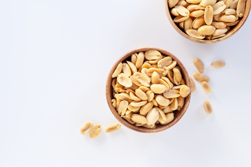 Roasted salted peanuts in wooden bowl on white background.