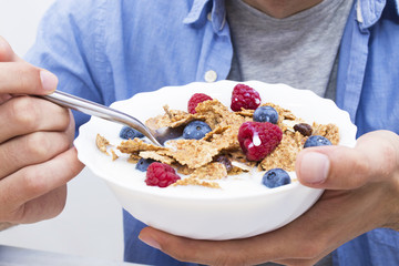 young man eating cereal with fruit