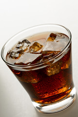 Cola in glass with ice on white background