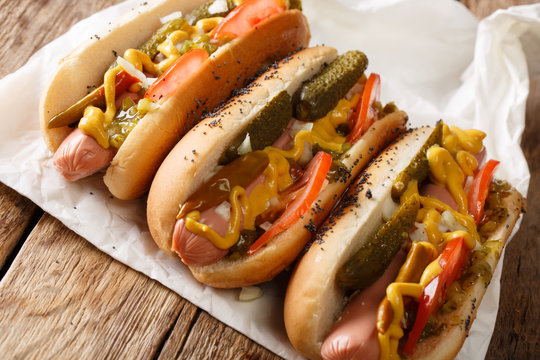 Homemade Chicago style hot dogs with mustard, tomatoes, pickled cucumbers, onions and relish close-up. horizontal