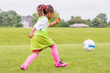 A young girl is learning how to play soccer