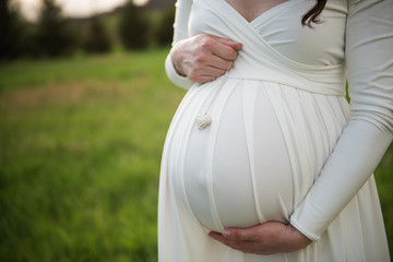 woman wearing white dress holding pregant belly 