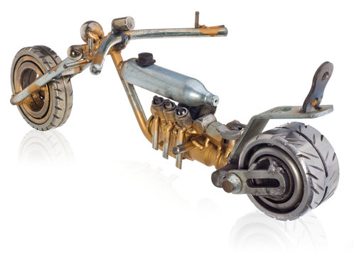 Handmade miniature of a chopper motorcycle. Decorative vehicle made of mechanical parts, bearings, wires, car candles, screws, plates. Toy in silver-gold colors, isolated on a white background.