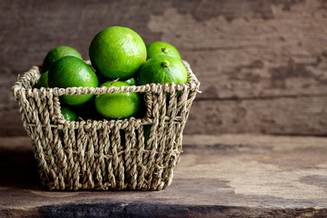Fresh limes in the basket on a wooden background