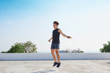 Man jumping on the jumping rope. Young asian descent men with naked torso jumping on the jumping rope outdoors © makistock