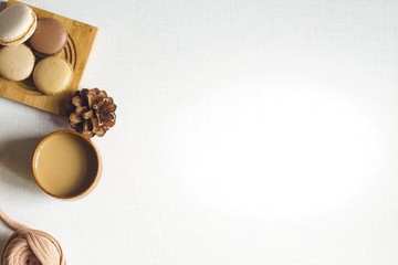 Top view of a cookie with latte and spruce cone and a yarn. Espresso, four cookies and spruce cone and a tangle on the white desk. Sunny morning. Flat lay with copy space for text.