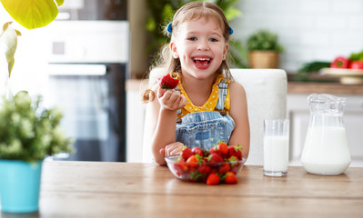 happy child girl eating strawberries with milk  .
