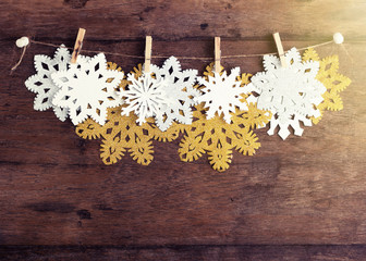Golden, silver and white paper snowflakes with clothespin on twine on rustic wooden background. New year, christmas concept. Text space