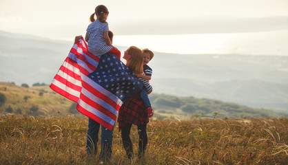 happy family with flag of america USA at sunset outdoors.