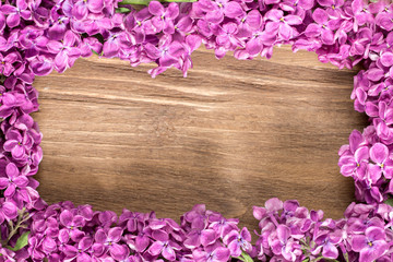 Lilac flowers lie on the wooden surface. Lilac flowers frame composition.