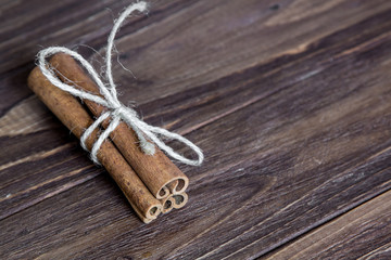 three cinnamon stick tied with rope, at the brown wooden table