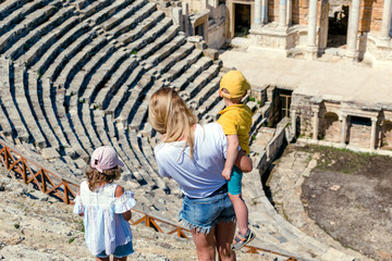 Young woman with childs looks at the ancient amphitheater in Hierapolis, Turkey. Female traveler visits landmark of Turkey.