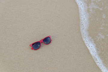 Fototapeta na wymiar A red sun glasses at the beach,A red sun glasses on the sand.