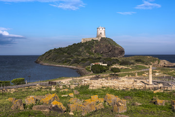 Ancient tower situated on a hill at the mediterranean sea with the ruins of Tharros in front, Sardinia, Italy