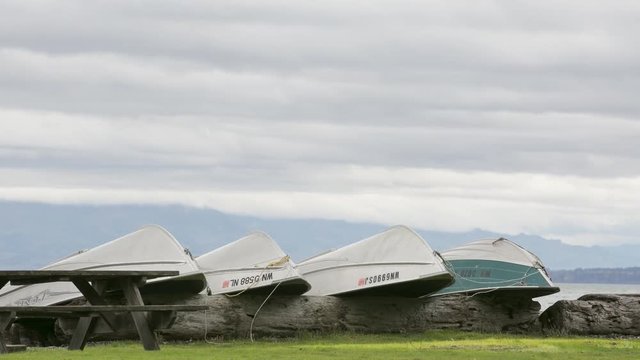 Rowboats beached on log for winter with storm clouds moving overhead on Washington's Puget Sound.