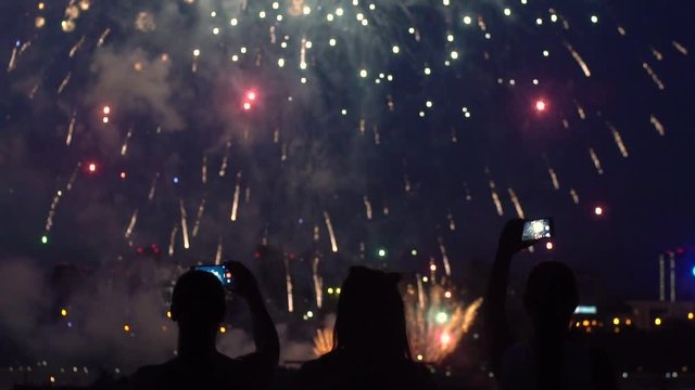 A group of people are happy during the beautiful fireworks using smartphones. slow motion.