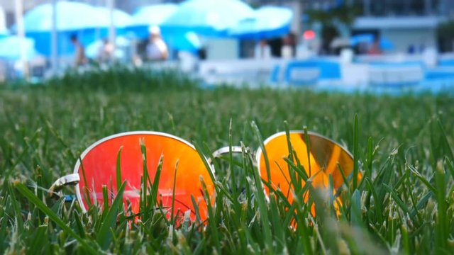 Sunglasses in the green grass. Reflections of the hotel and the beach near the sea. TimeLapse.