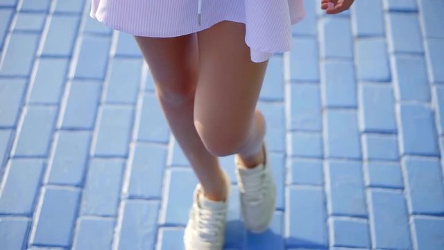 Close up shot of woman's lovely long legs in sneakers.
