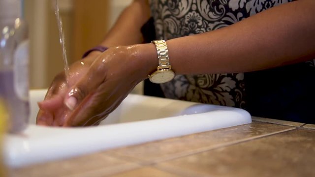 Close-up of black woman washing her hands at a kitchen sink
