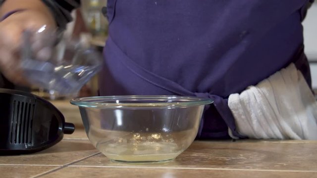 Woman adds ingredients to a glass bowl and blends with an electric mixer, Close-up