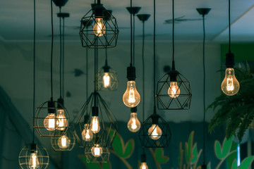 A lot of vintage lamps hanging from the ceiling. Beautiful lighting decor, toned image.