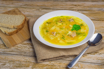 A plate of tasty pea soup with a spoon and pieces of bread on a rustic wooden table.