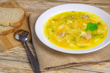 A plate of tasty pea soup with a spoon and pieces of bread on a rustic wooden table.