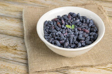 White bowl of honeysuckle berry on a wooden rustic table.