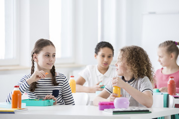 Children during snack time in their classroom. Bottles of fruit and vegetable juices on the desks....