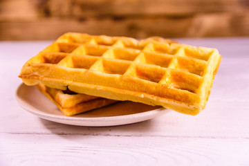 Ceramic plate with belgian waffles on wooden table