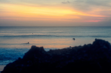 Beautiul sunset on a tropical island. Surfers enjoying challenges of surfing.