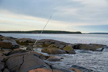 the fishing pole is on a rocky shore