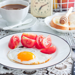 Breakfast of fried eggs, fresh tomatoes, coffee, bread, square