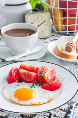 Breakfast of scrambled eggs, fresh tomatoes, coffee with milk, bread with honey, selective focus