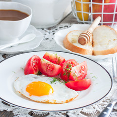 Breakfast of fried eggs, fresh tomatoes, coffee, bread, square