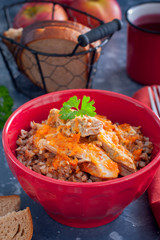 Buckwheat porridge with meat in a red bowl, selective focus