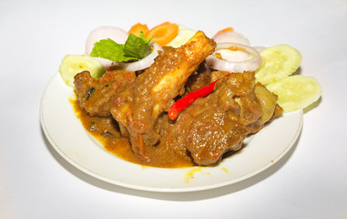Popular Indian meal of spicy mutton meat gravy popularly known as mutton kosha with chili and sliced vegetables.