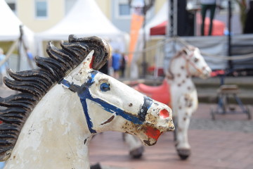 Fototapeta na wymiar Hölzerne Schaukelpferde auf einem Marktplatz