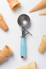 Fototapeta na wymiar Clean empty vintage ice cream scoop spoon on white table flatlay with wafer cones
