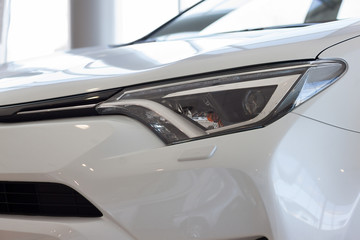 New white vehicle with elegant head lamps in showroom.