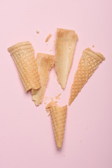 Crushed empty ice cream waffle cone on pink pastel background