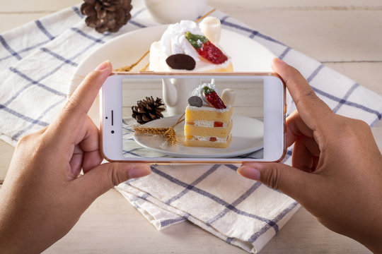 Photographing food concept - takes picture of cake with Smartphone