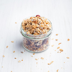 Granola in mason jar on the white wooden table. Shot at angle.