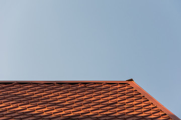 the top of the roof of an iron tile against the background of a blue sky