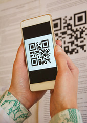 Two woman hands scanning QR code using smart phone