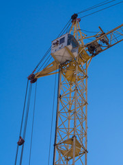 Partial view of a yellow construction crane against blue background