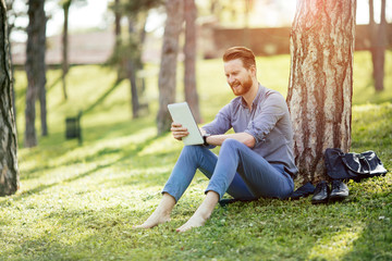 Fototapeta premium Handsome student reading in nature