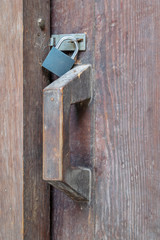 Closeup of a wooden aged latch locked with a padlock in a wooden door