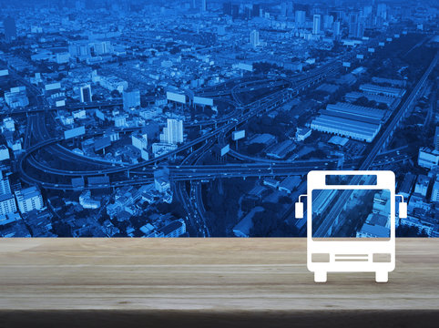 Bus flat icon on wooden table over modern city tower, street and expressway, Business transportation service concept