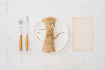 Fototapeta na wymiar Eating concept. Spoon, fork and white dish on white stone background.